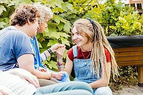 Eine junge Frau mit Dreadlocks im Gespräch mit zwei Frauen