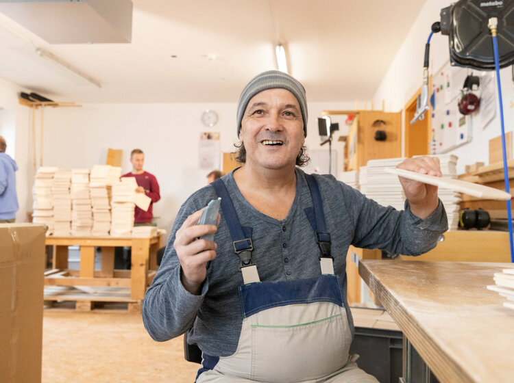 Ein Mitarbeiter einer Schreinerei bearbeitet Holz