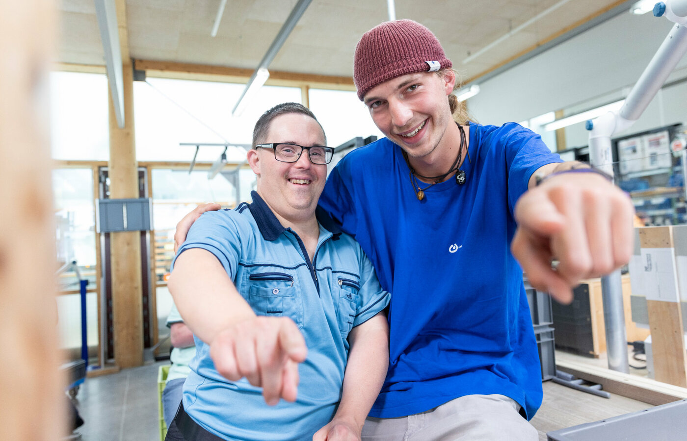 Ein Mitarbeiter der Lebenshilfe Lindau und ein Klient zeigen in die Kamera