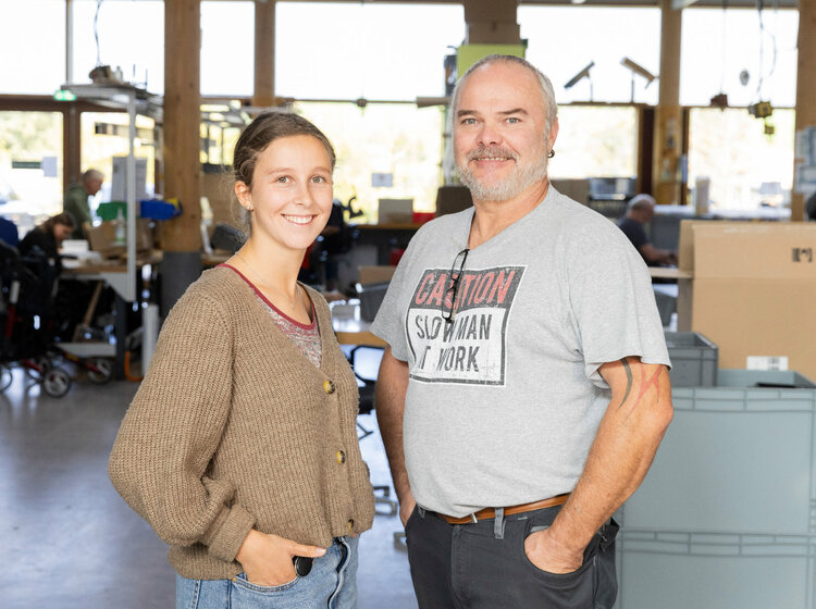 Zwei Personen stehen nebeneinander in einer Werkstatt