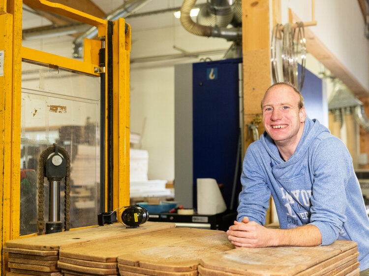 Ein Mann transportiert Holzbretter in einem Holzlager