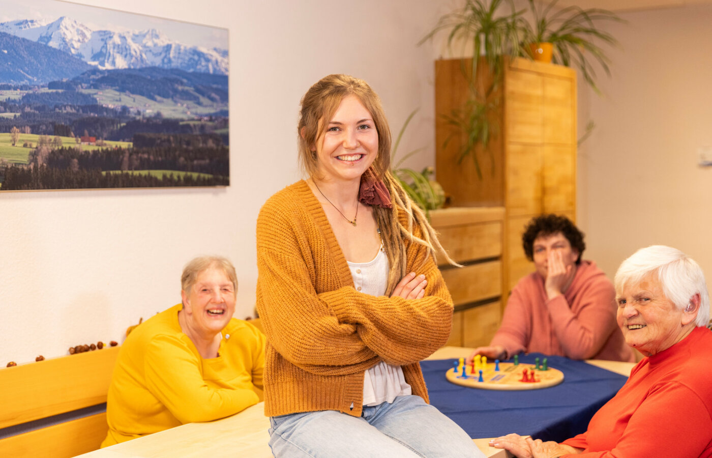 Eine Frau mit Dreadlocks und ältere Frauen sitzen gemeinsam am Esstisch