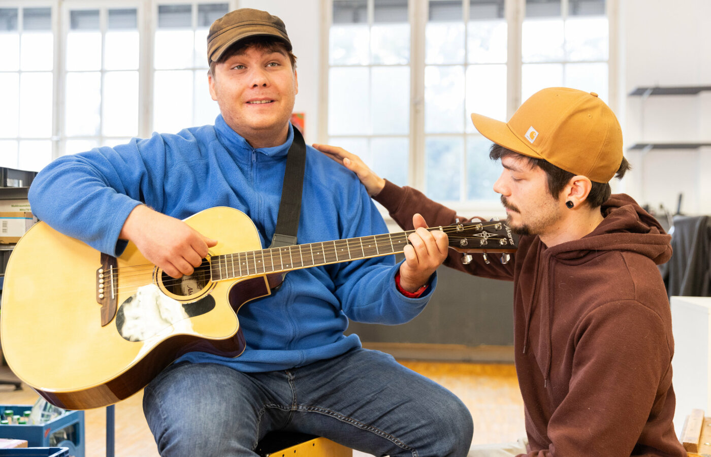 Ein Mann spielt Gitarre, ein anderer hört zu.