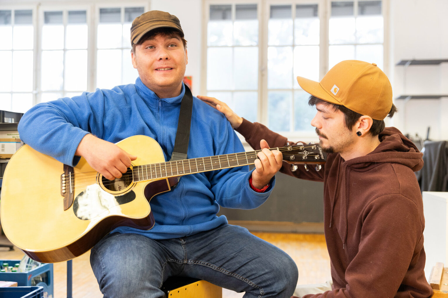 Ein Mann spielt Gitarre, ein anderer hört zu.