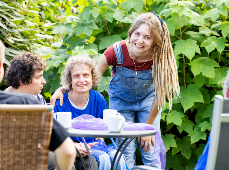 Mehrere Personen sitzen um einen Gartentisch herum