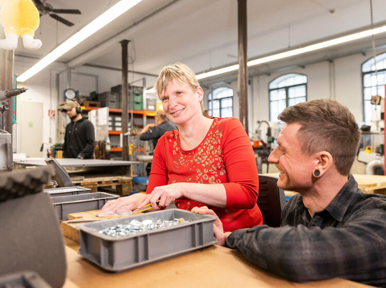 Eine Frau entgratet Metallteile mit einer Feile