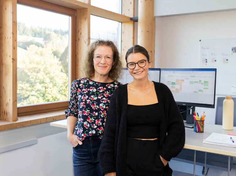 Zwei Frauen stehen nebeneinander in einem Büro