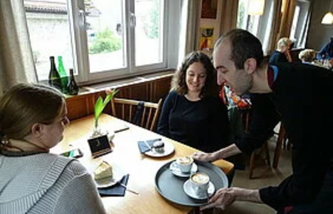 Ein Kellner serviert Getränke im Cafe Inklusiv in Wasserburg