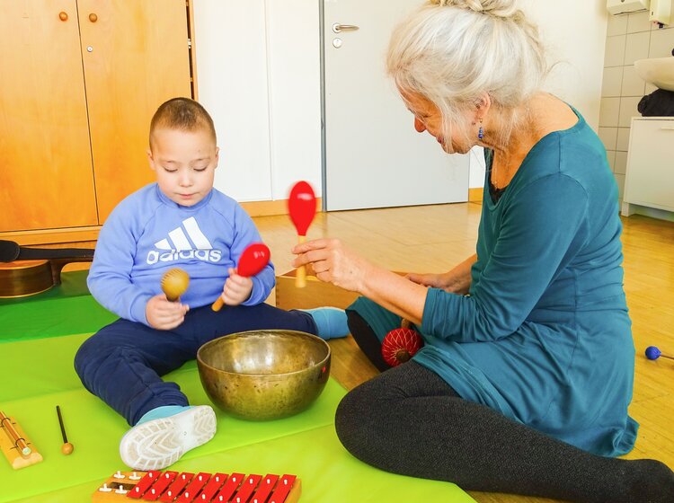 Ein Kind macht Musik mit Rasseln