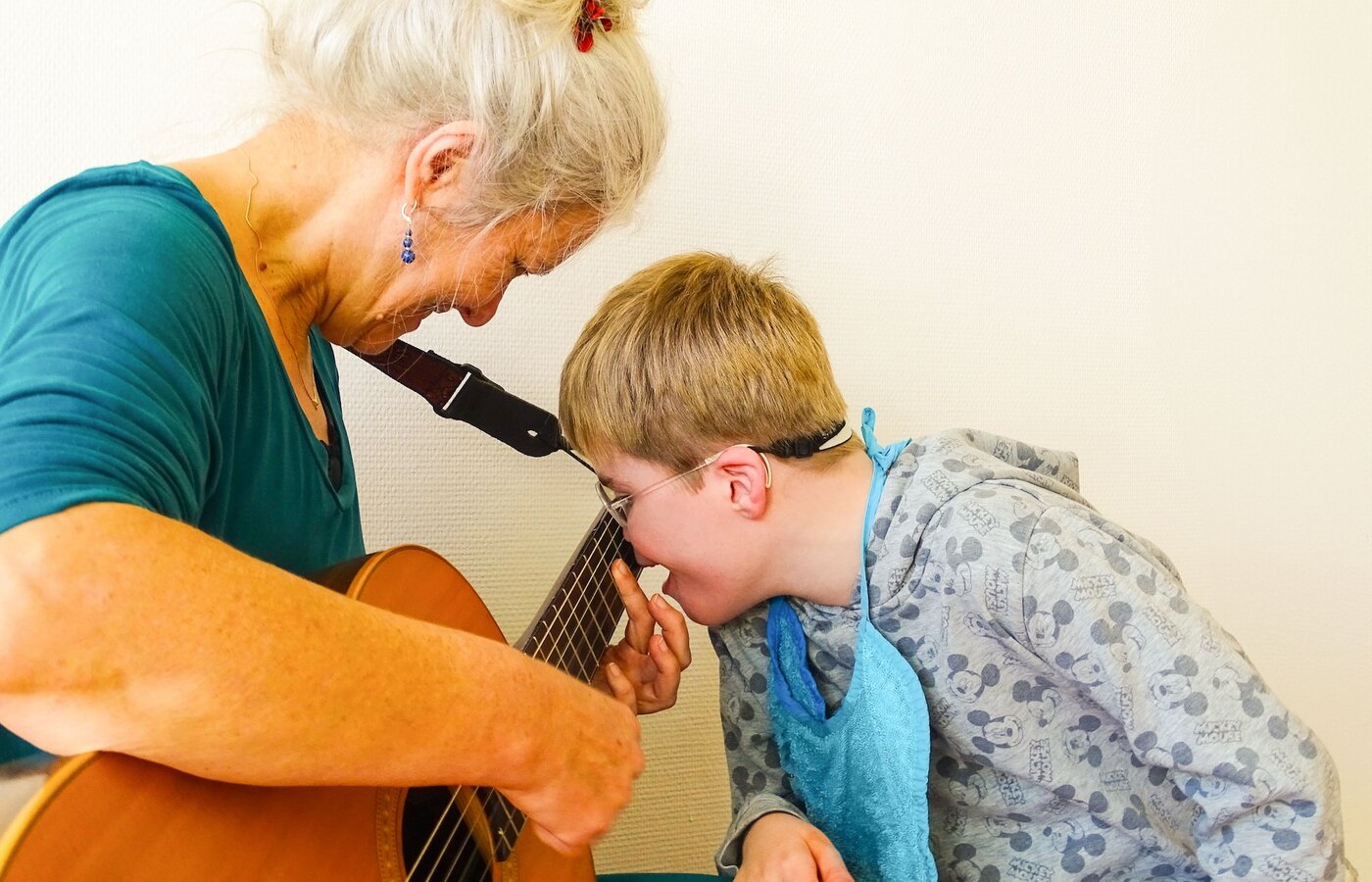 Eine Frau spielt zusammen mit einem Kind auf einer Gitarre