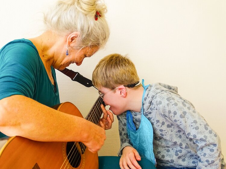 Eine Frau spielt zusammen mit einem Kind auf einer Gitarre