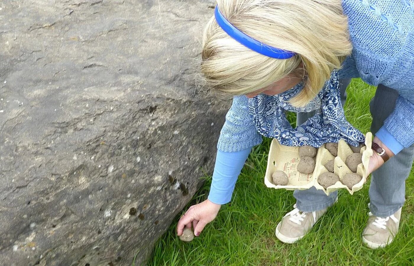 Eine Frau platziert Samenbomben auf einer Wiese