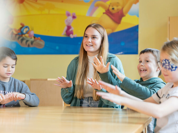 Eine Frau und Kinder singen an einem Tisch zusammen