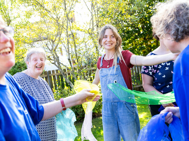 Mehrere Frauen machen Gymnastik mit Tüchern im Garten