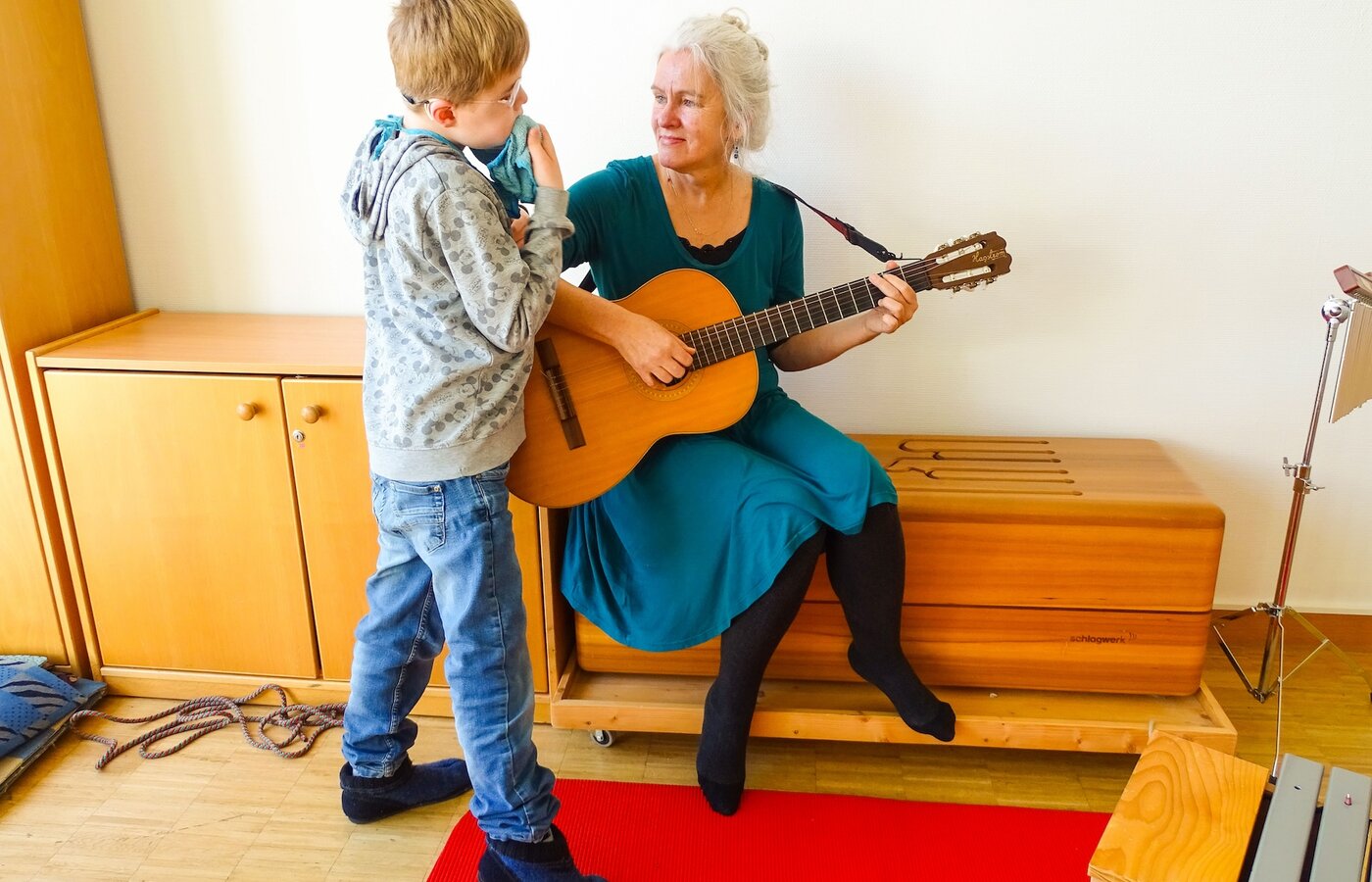 Eine Frau musiziert gemeinsam mit einem kleinen Jungen auf der Gitarre